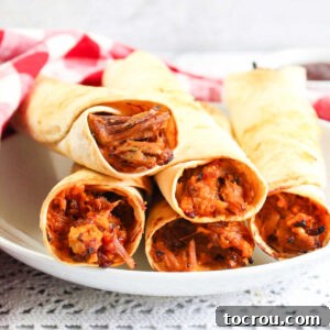 Close up of bbq pulled pork filling inside crispy tortilla taquitos, ready to eat.
