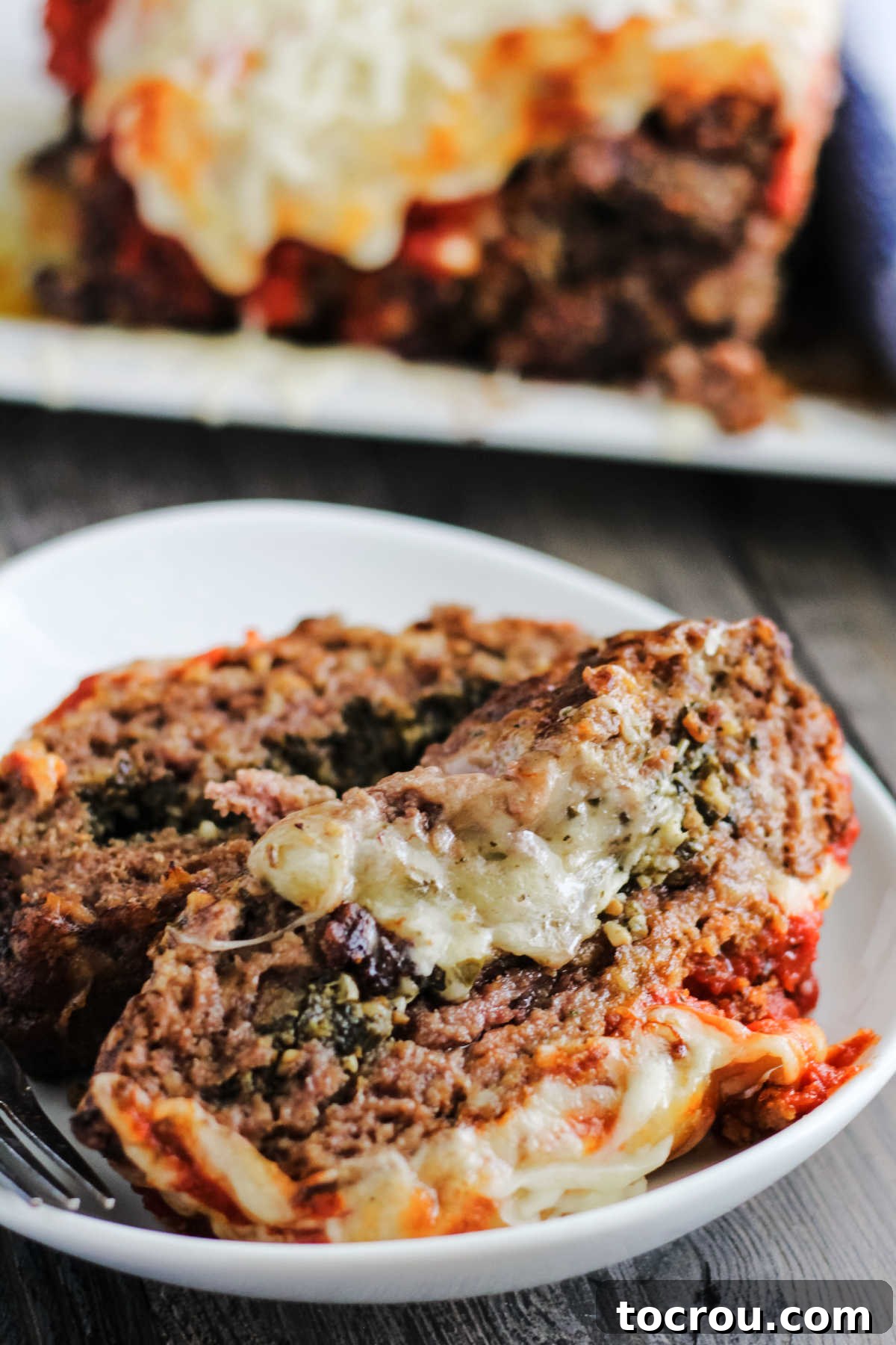 Slices of meatloaf stuffed with melted cheese and pesto topped with marinara sauce and more melted mozzarella.
