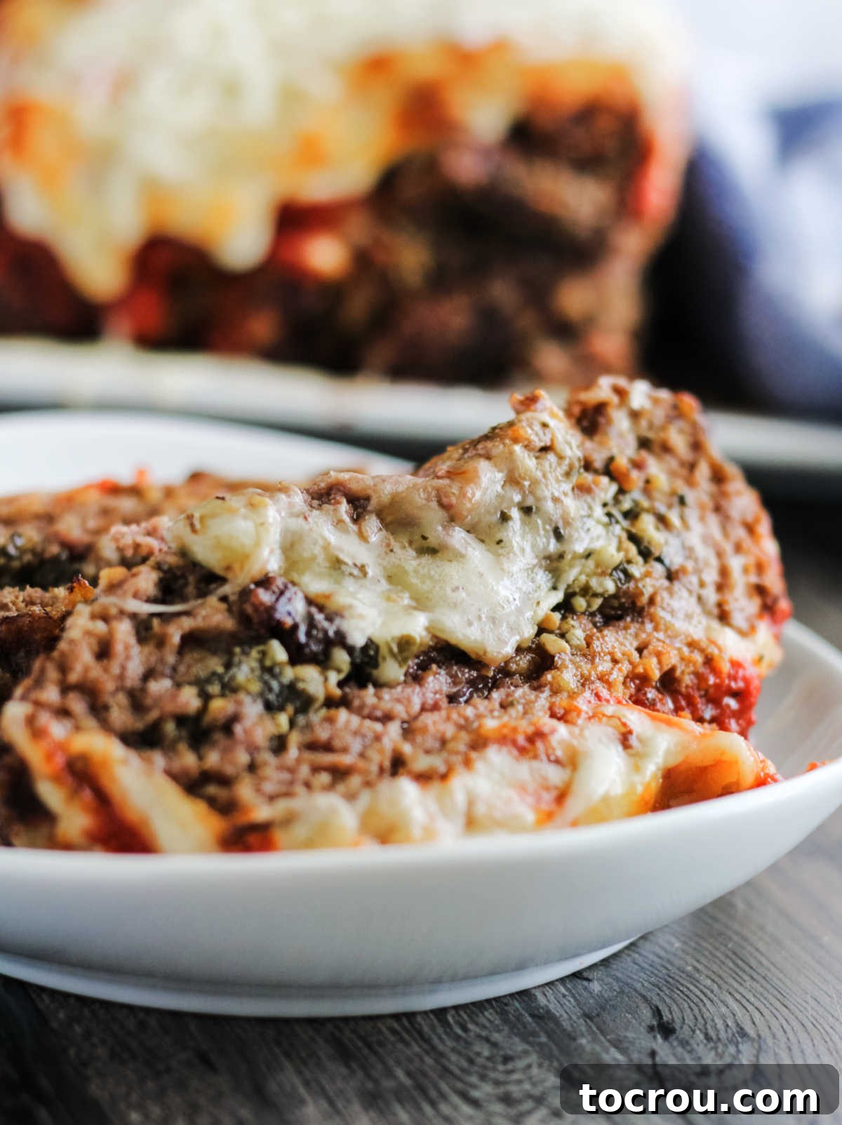 Plate of cheese stuffed meatloaf slices with remaining meatloaf in background.