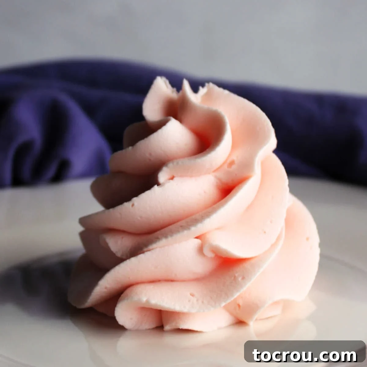 Swirl of light pink lemonade frosting, showcasing its beautiful texture and color.