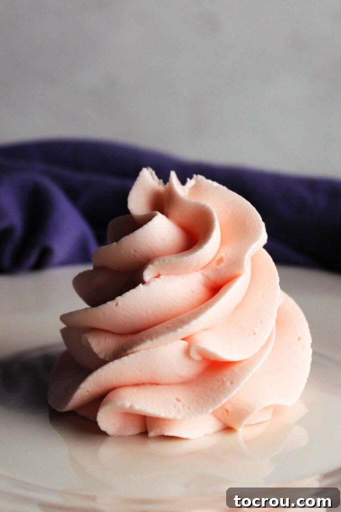 Big fluffy pile of piped swirl of pink lemonade buttercream frosting, ready to be enjoyed.