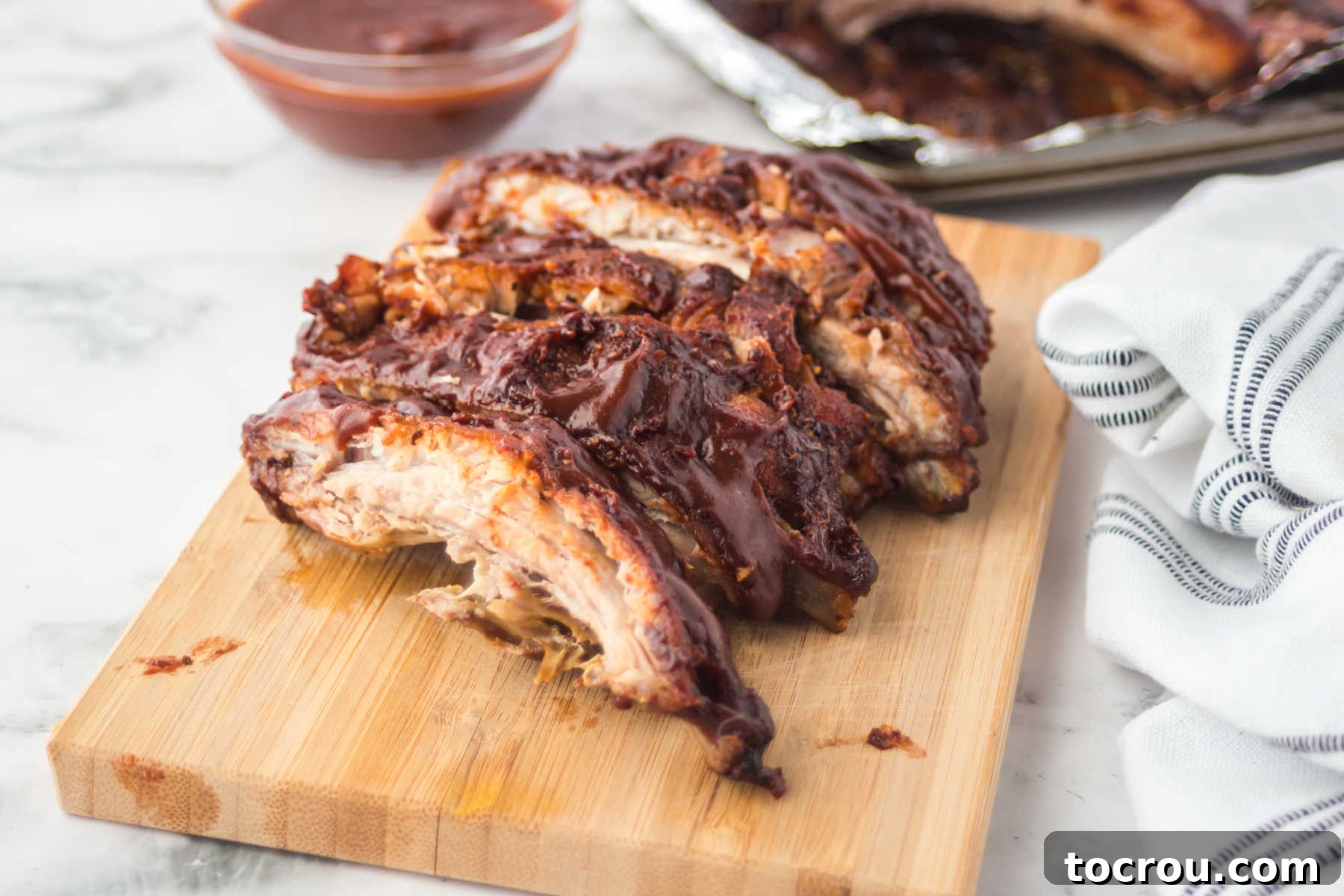 Mouthwatering Oven Baked Ribs 2 Cutting board with baked bbq ribs on top, cut into individual ribs, ready to eat.