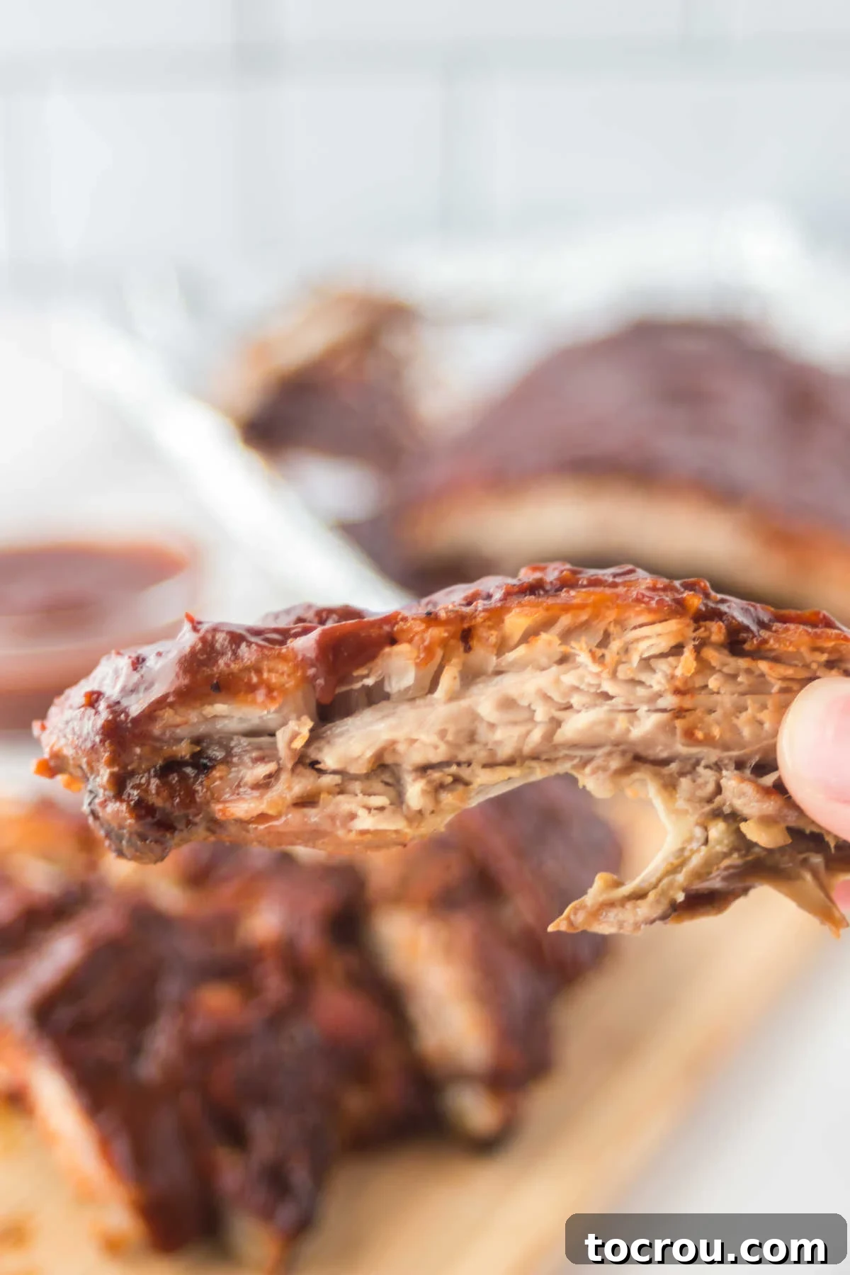 Mouthwatering Oven Baked Ribs 7 Hand holding bbq sauce coated rib.