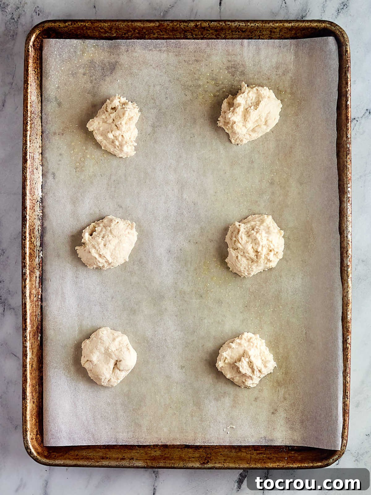 Fluffy Biscuits and Rich Sausage Gravy 6 Six perfectly formed biscuit dough pieces arranged on a parchment-lined baking sheet, ready for the oven to achieve golden perfection.