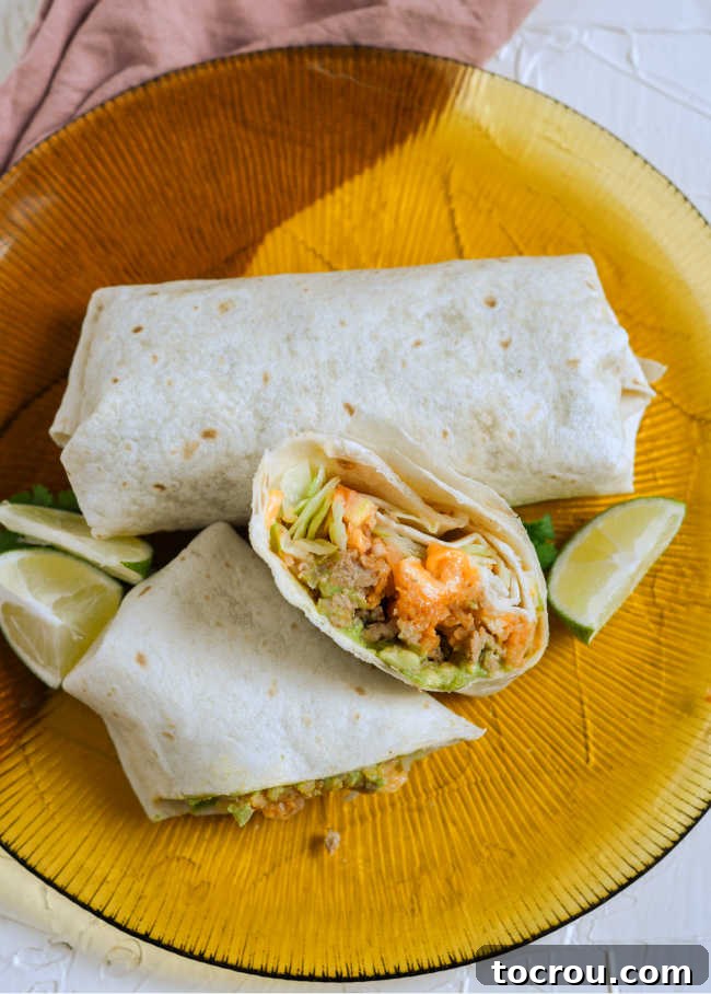 cut burrito on plate with lime wedges, ready to eat