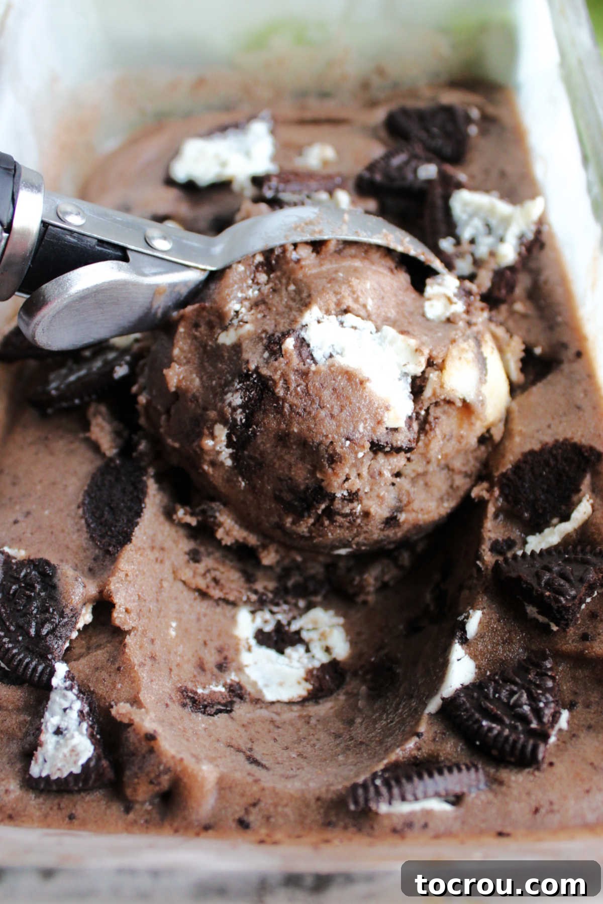 Getting a scoop of chocolate banana nice cream with chunks of Oreo cookies in it.