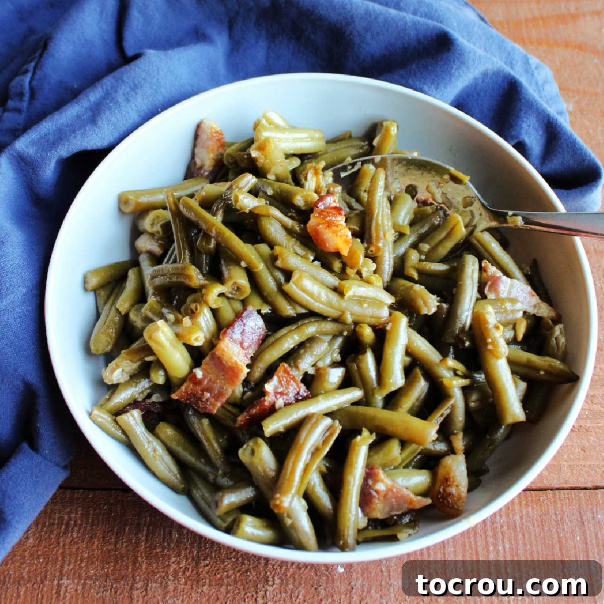 Homestyle Slow Cooker Smothered Green Beans 2 Serving bowl filled with shiny green beans and bacon smothered in sweet and sour sauce ready to eat.