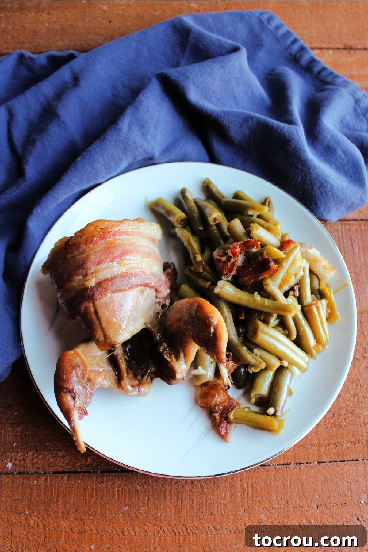 Golden Roasted Bacon Wrapped Quail 8 Smothered green beans on plate with bacon wrapped quail.