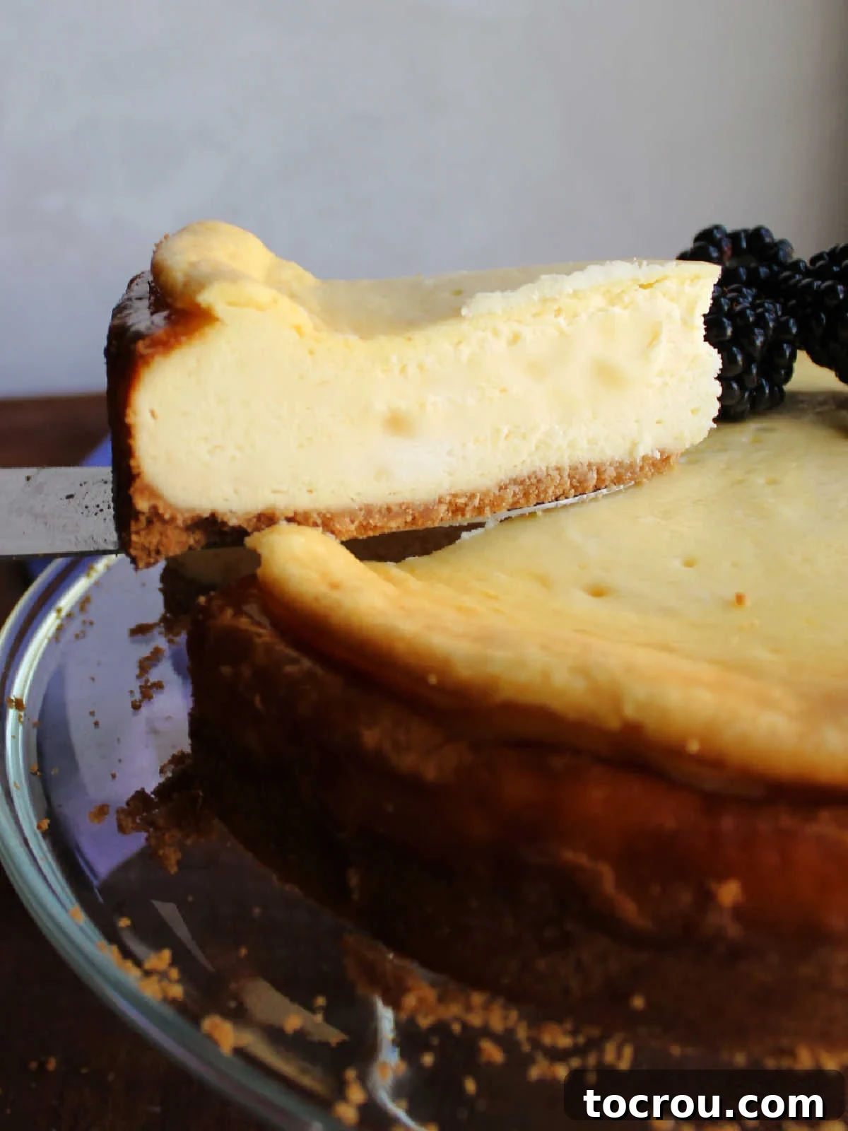 A slice of creamy condensed milk cheesecake being lifted from the larger cake, revealing its perfectly smooth filling and rich texture.