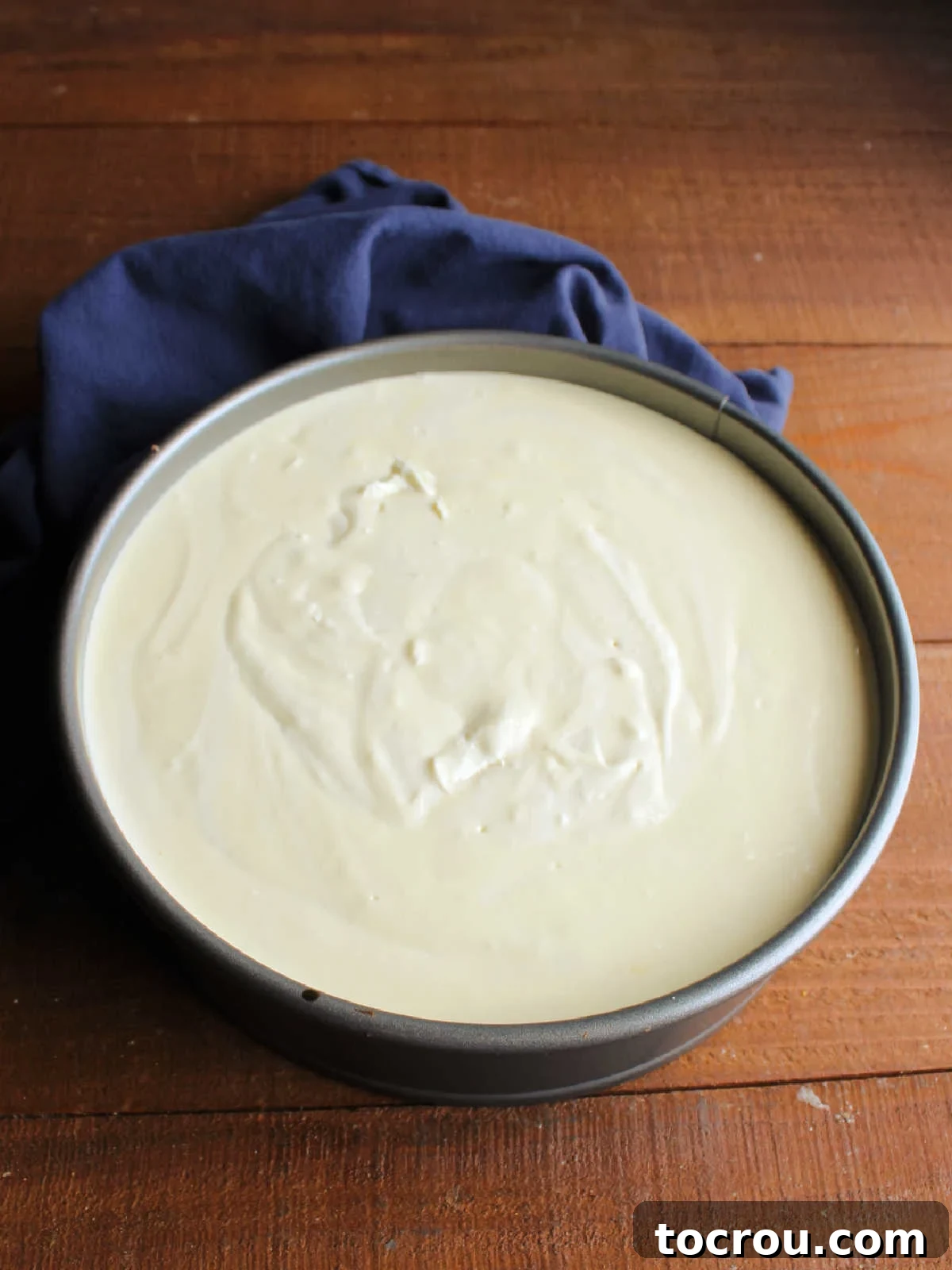 Cheesecake batter smoothly poured into a springform pan with a pre-baked crust, ready for the oven.