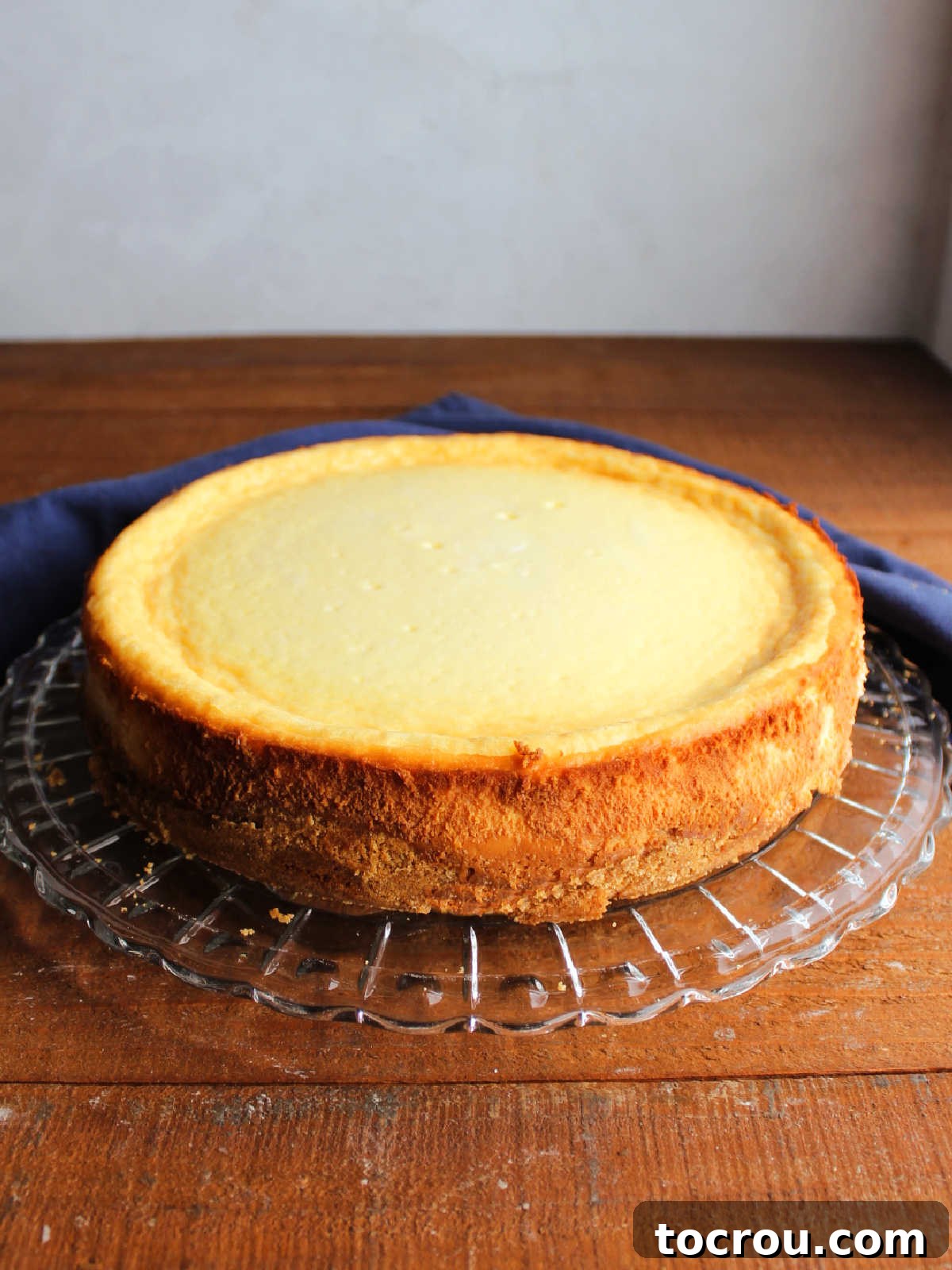 Whole condensed milk cheesecake presented on a glass serving platter after being removed from the springform pan.