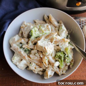 Close up of a bowl of crockpot penne with chicken, broccoli, and creamy alfredo sauce.