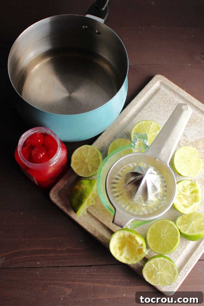 Cherry Limeade Ingredients Ingredients laid out for making limeade: fresh limes, bright red maraschino cherries, and a bowl of sugar water.