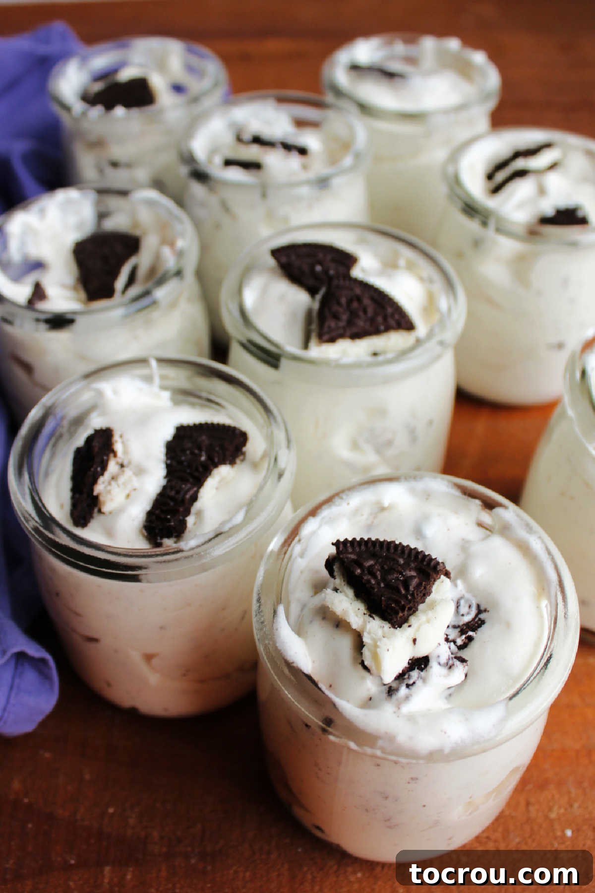 Oreo Fluff Served in Jars Individual serving jars filled with layered Oreo fluff salad, each topped with a sprinkle of crushed Oreo cookies. The light, whipped texture is visible, making them appealing single-serve treats.