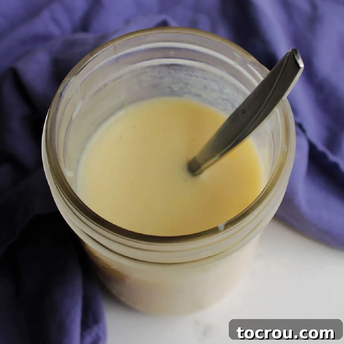 Looking down into jar of sweetened condensed milk with spoon.