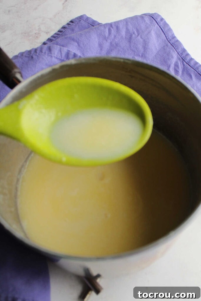 Spoonful of hot sweetened condensed milk over saucepan.