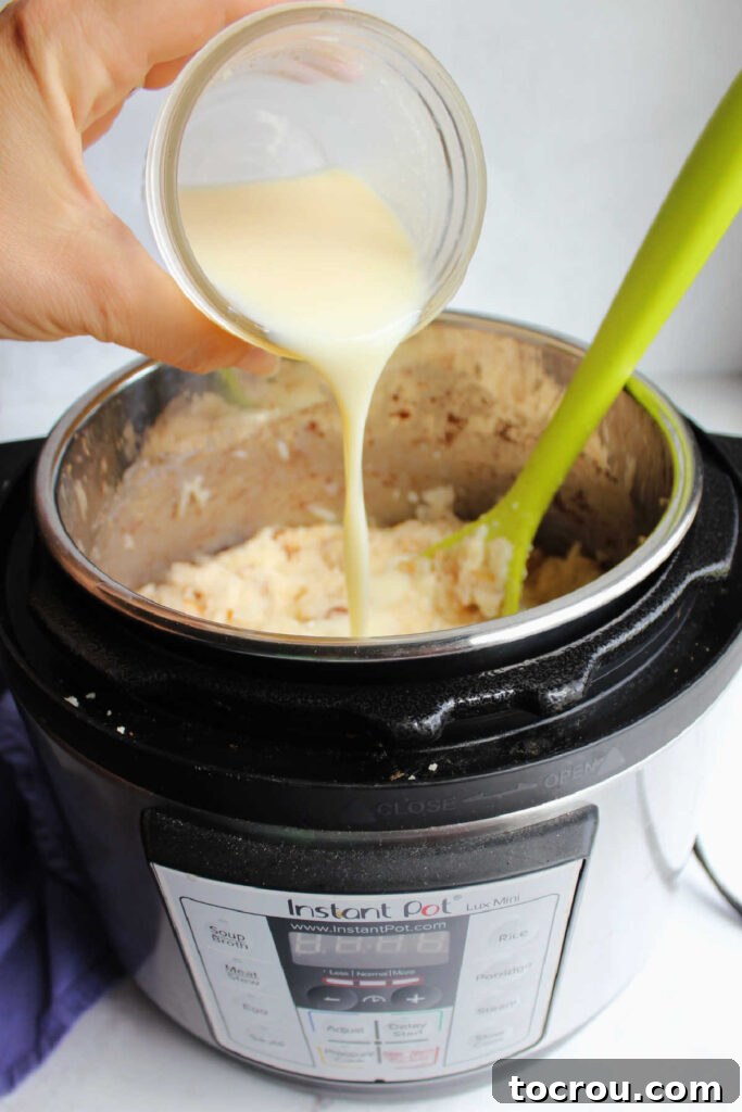 Pouring jar of homemade sweetened condensed milk into instant pot with cooked rice mixture.