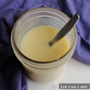 Looking down into jar of sweetened condensed milk with spoon.