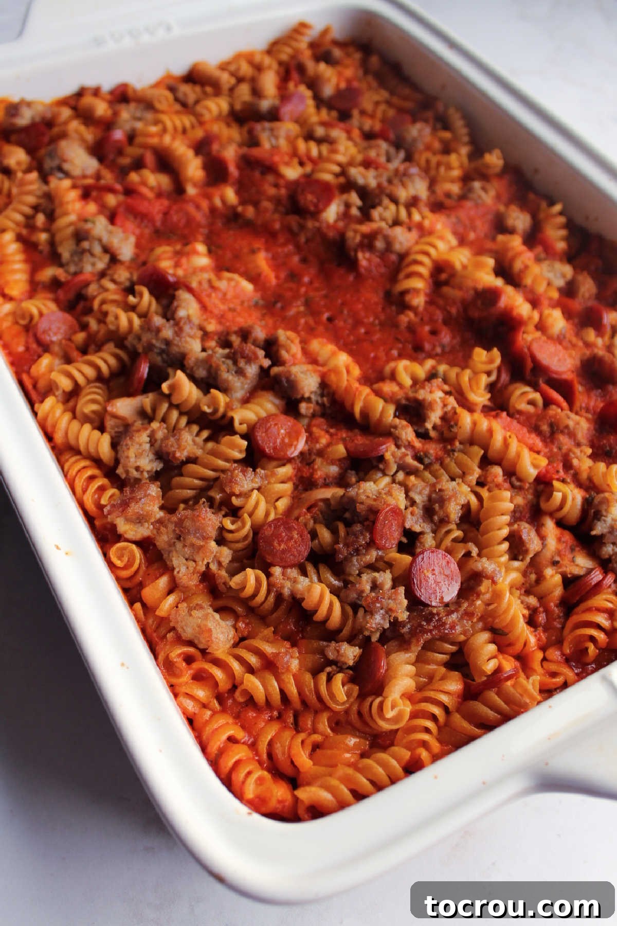Partially baked casserole with most of the liquid absorbed, ready for cheese and to finish cooking, showing progress.