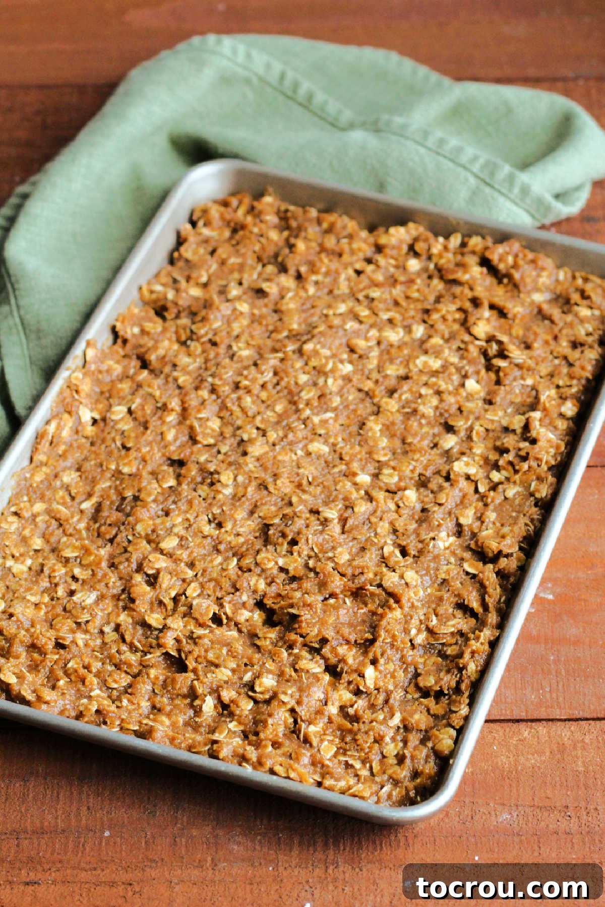 Oatmeal cream pie bar dough spread out in 10x15-inch pan, ready to bake.