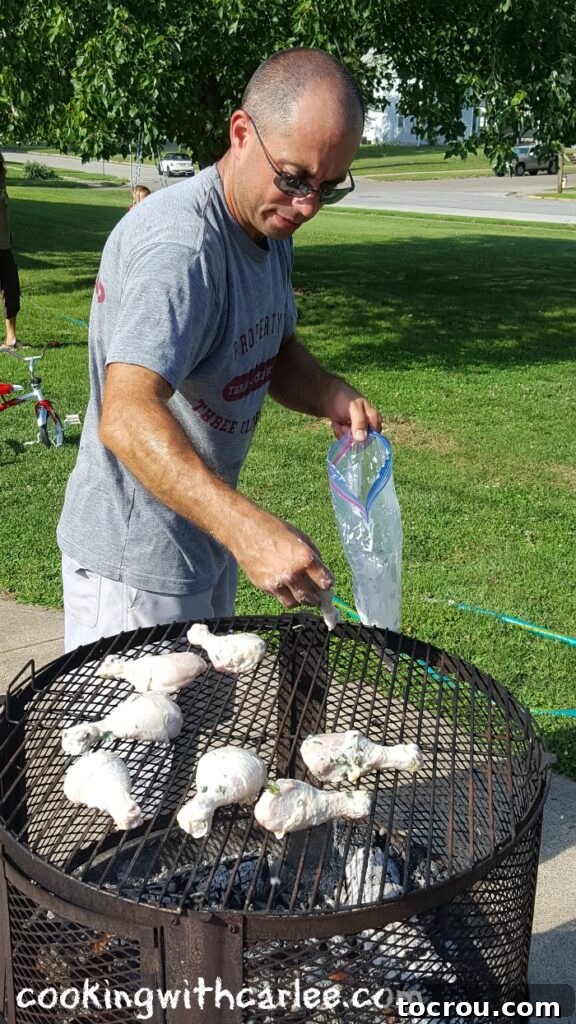 Grilling Lemon Yogurt Chicken Over Wood Fire A person placing yogurt-marinated chicken drumsticks onto a hot wood-fired grill, showing the grilling process and glowing embers.