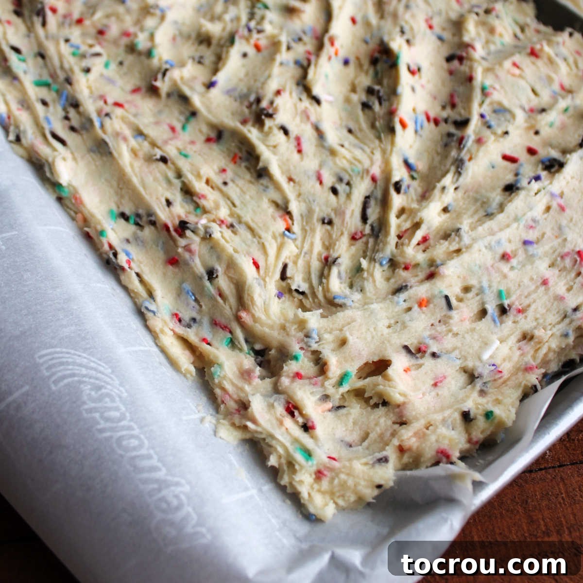 Party Sugar Cookie Bars 4 Vibrant sprinkle-filled cookie dough evenly pressed into a sheet pan, ready for baking.
