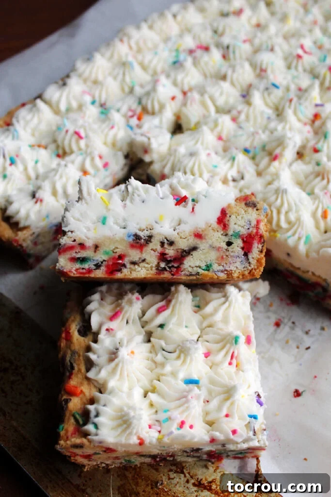 Party Sugar Cookie Bars 8 Close-up side view of a funfetti sugar cookie bar, highlighting the soft cookie texture, baked-in sprinkles, and a thick layer of frosted sprinkles.