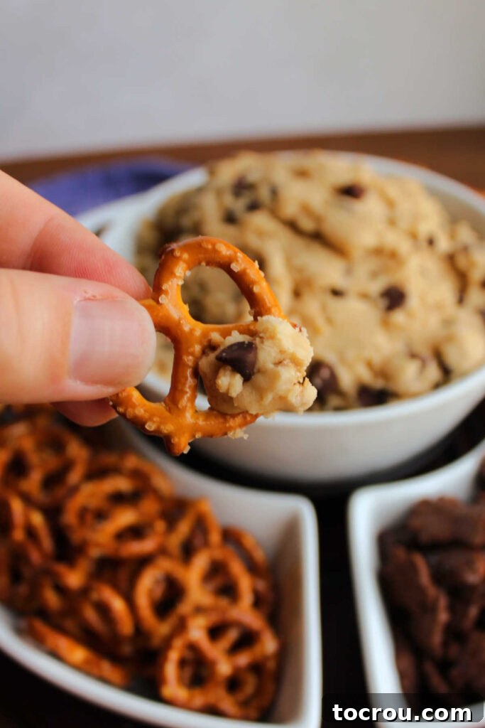 Pretzel Dipped in Cookie Dough Dip A tantalizing image of a crunchy pretzel twist expertly dipped into the creamy chocolate chip cookie dough dip, highlighting the perfect sweet and salty combination.