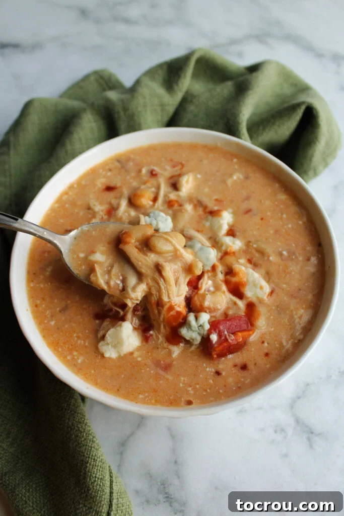 Spoonful of Creamy Buffalo Chicken Chili Spoonful of creamy buffalo chicken chili being lifted out of bowl, ready to eat.