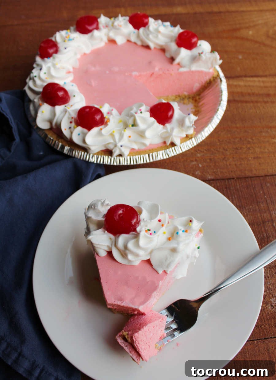 Fork with a bite of pink jello pie on it, next to a creamy cherry jello pie slice.