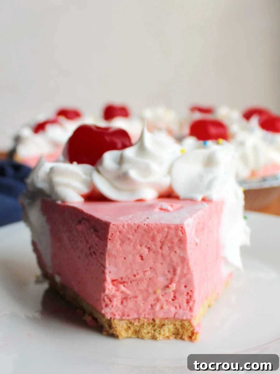 Bite missing from tip of cherry jello pie, revealing its airy and pink interior.