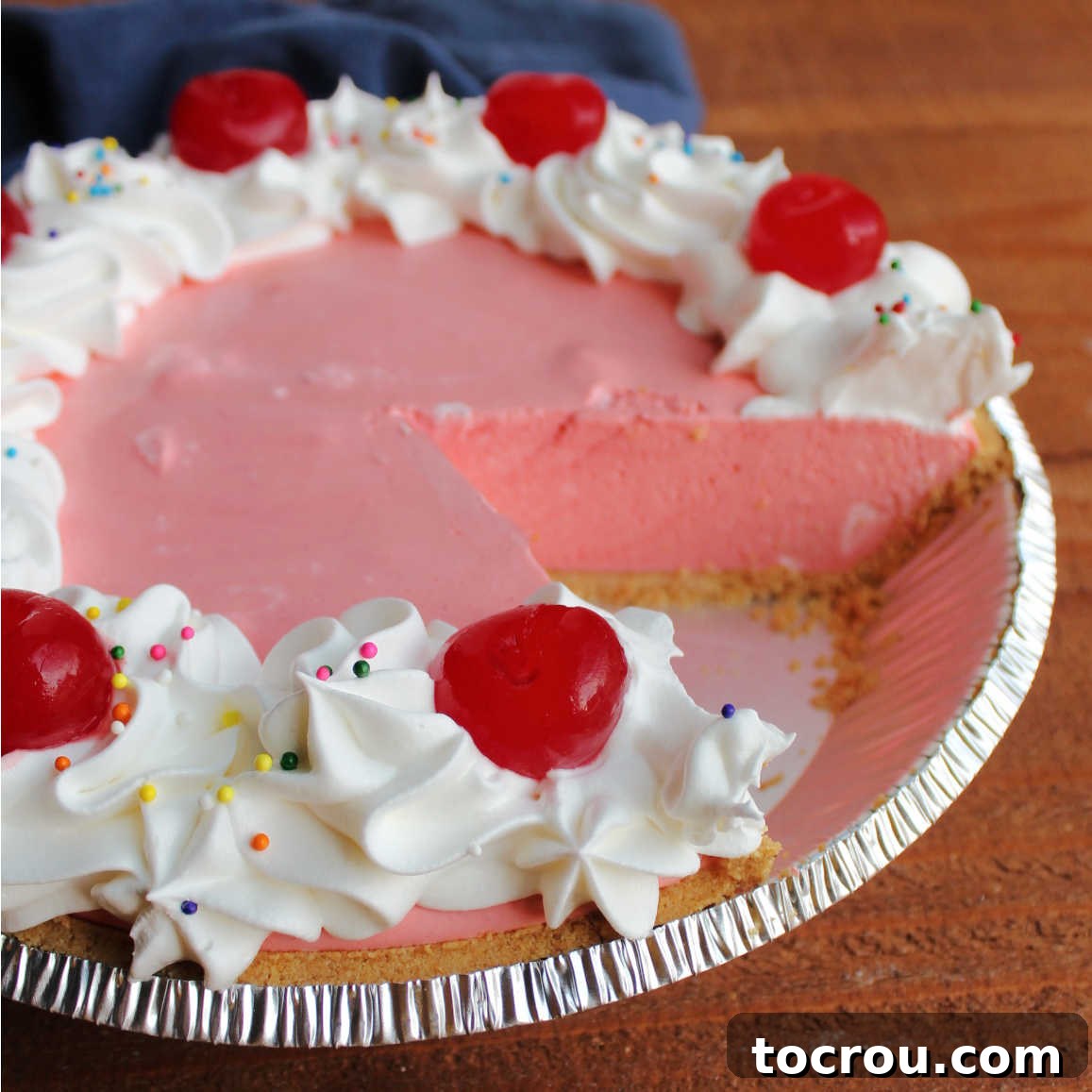 Pie plate with pink jello pie inside with a piece missing, ready to be enjoyed.