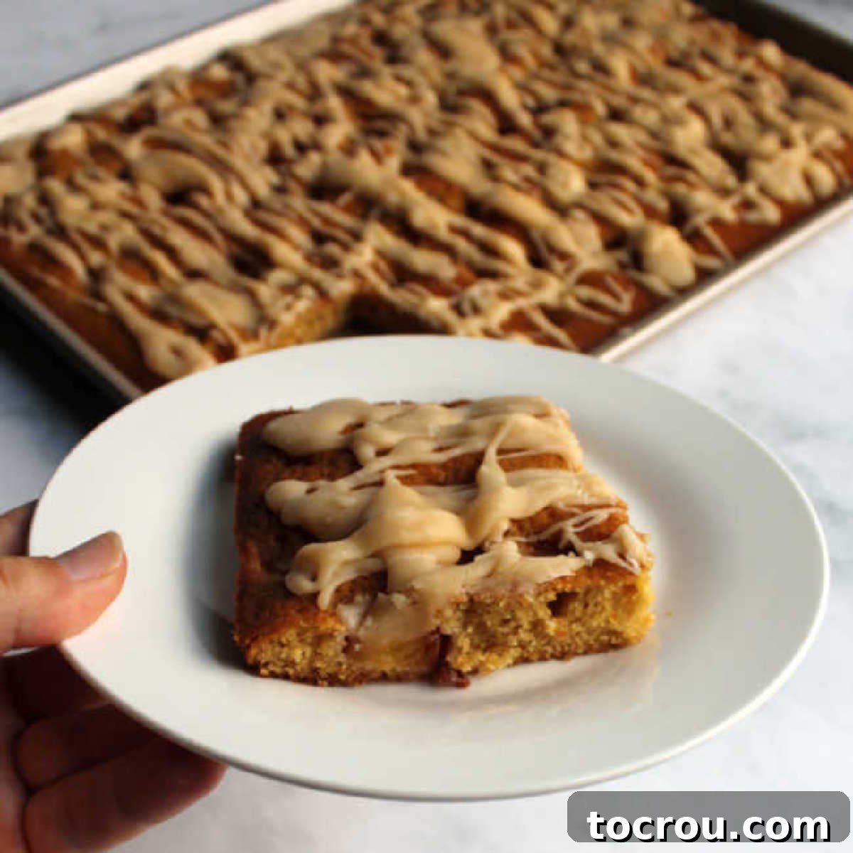 Nutty Brown Butter Glaze 2 Hand holding dessert plate with a piece of peach sheet cake drizzled with brown butter glaze.
