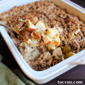 Spoon scooping out serving of apple crisp with condensed milk.