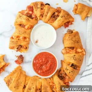 Pizza crescent ring served with a bowl of ranch and a bowl of marinara ready to eat.