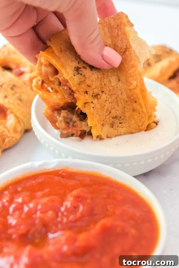 Hand dipping a piece of pizza wreath into a bowl of ranch dressing.