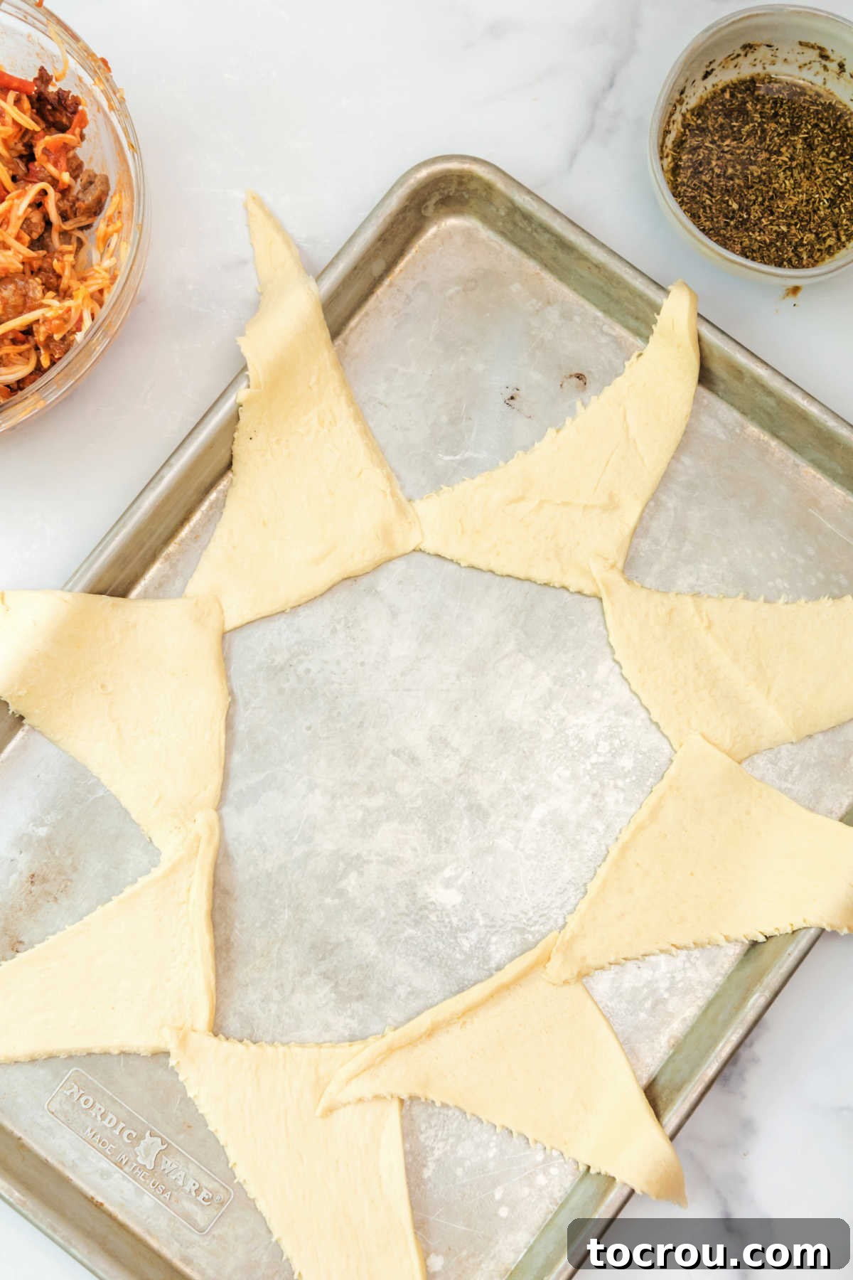 Single layer of crescent dough triangles on sheet pan.