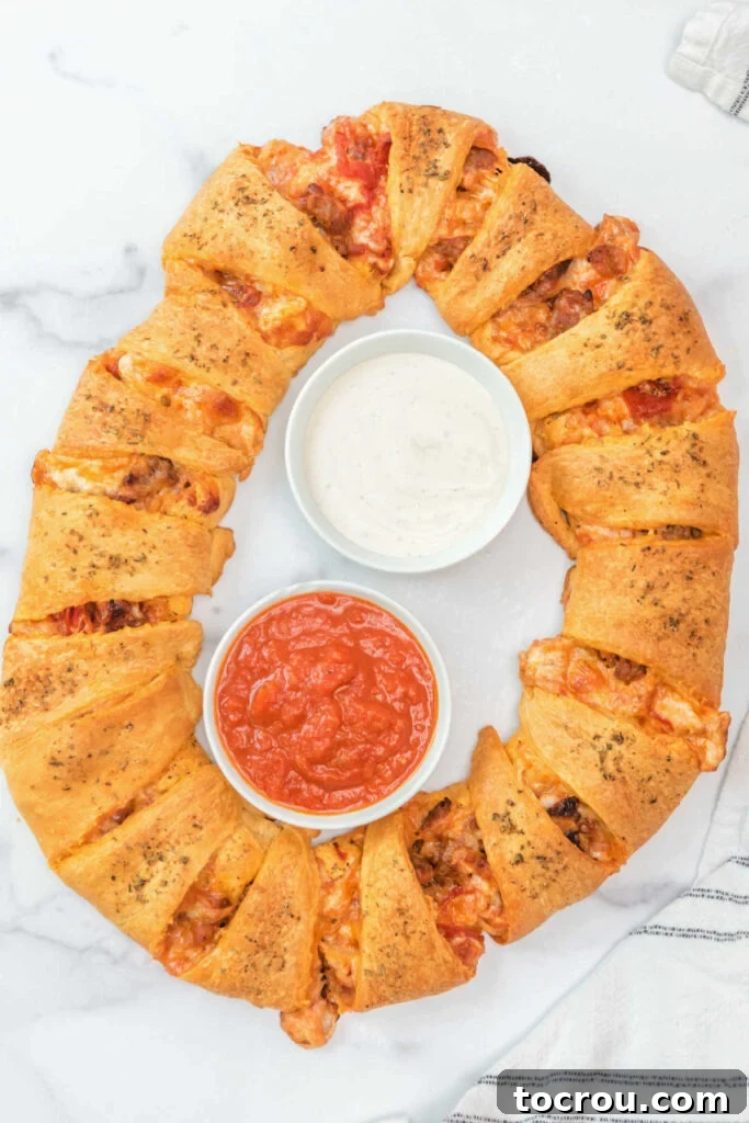 Freshly baked pizza pull apart wreath with a bowl of marinara sauce and a bowl of ranch in the middle ready to serve. 