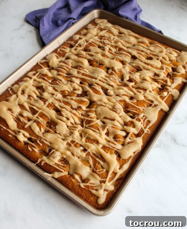 Summer Peach Sheet Cake 3 A beautifully baked whole peach sheet cake, artfully drizzled with a luscious golden-brown butter glaze, inviting you to take a slice.