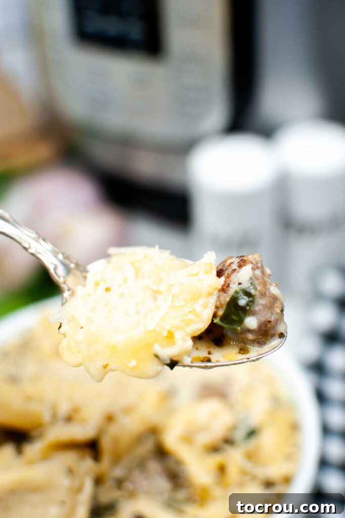 A spoonful of creamy tortellini soup, featuring tortellini, sausage, and spinach, lifted from the bowl.