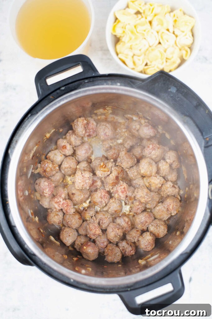 Italian sausage browning in an Instant Pot, forming a savory base for the soup.