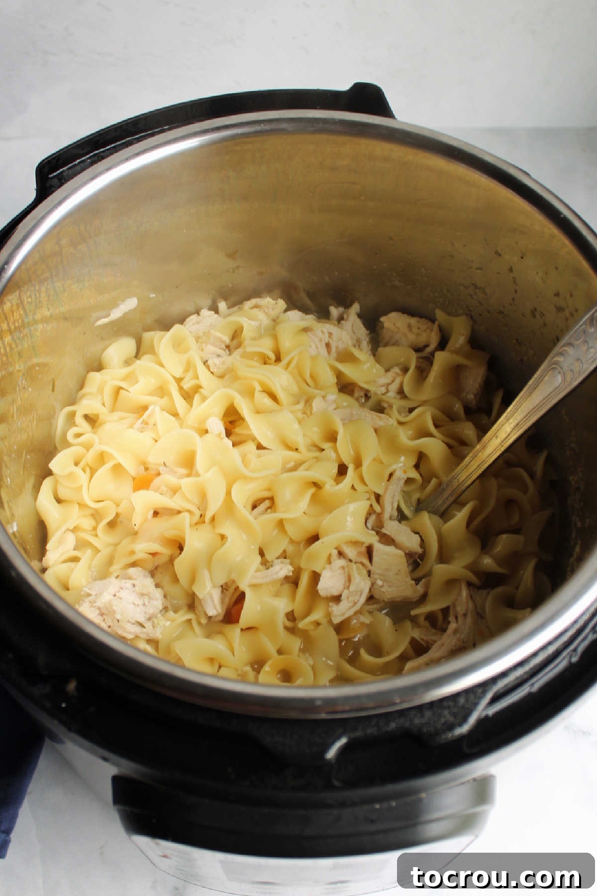 Flexible Chicken Noodle Soup: Instant Pot and Slow Cooker Ready 6 A large pot of chicken noodle soup, with freshly diced chicken stirred back into the rich, vegetable-filled broth, ready to be served, emphasizing its homemade appeal.