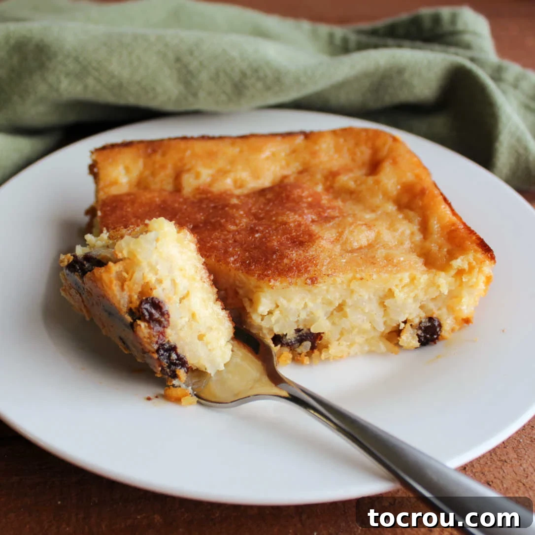 Velvety Condensed Milk Baked Rice Pudding 2 Bite of baked rice pudding with raisins on fork ready to eat.
