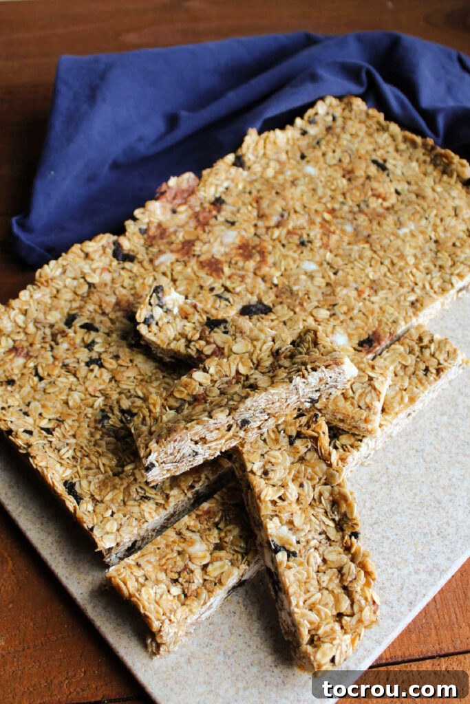 A perfectly stacked pile of homemade granola bars on a wooden cutting board, ready to be enjoyed.