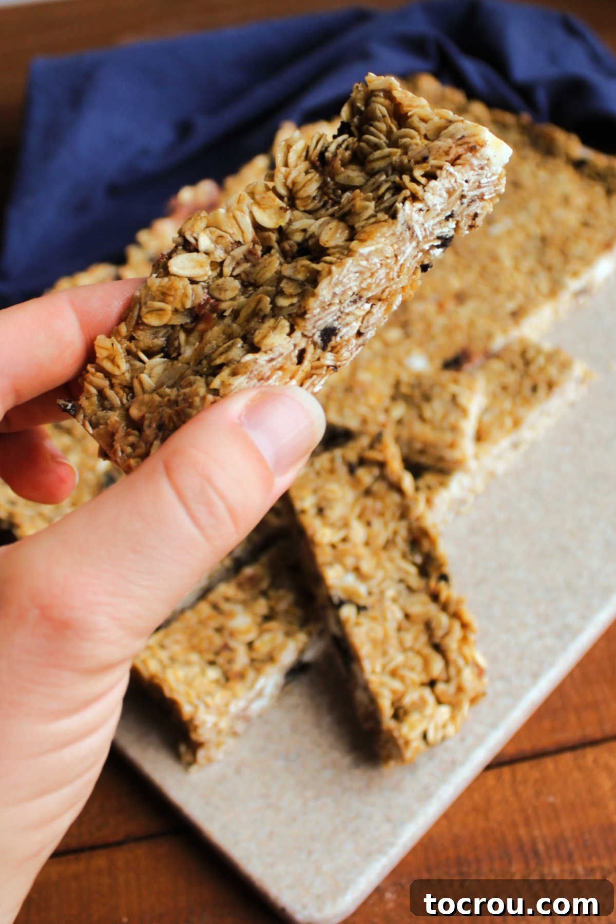 A hand proudly holding a homemade granola bar, clearly showing the enticing bits of crushed Oreo cookies and delicious chocolate chips embedded within.