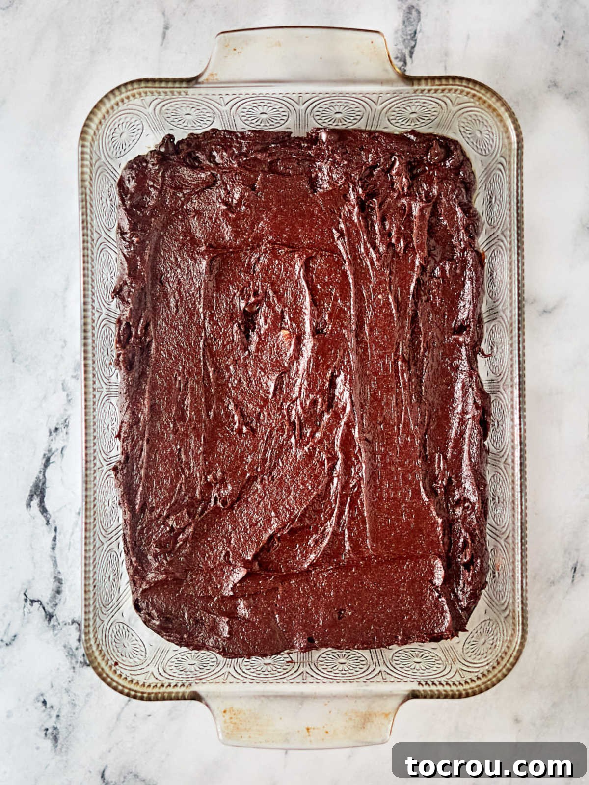 Brownie Batter in Pan Smooth brownie batter evenly spread in a 9x13-inch baking pan, ready to be placed in the oven for baking.