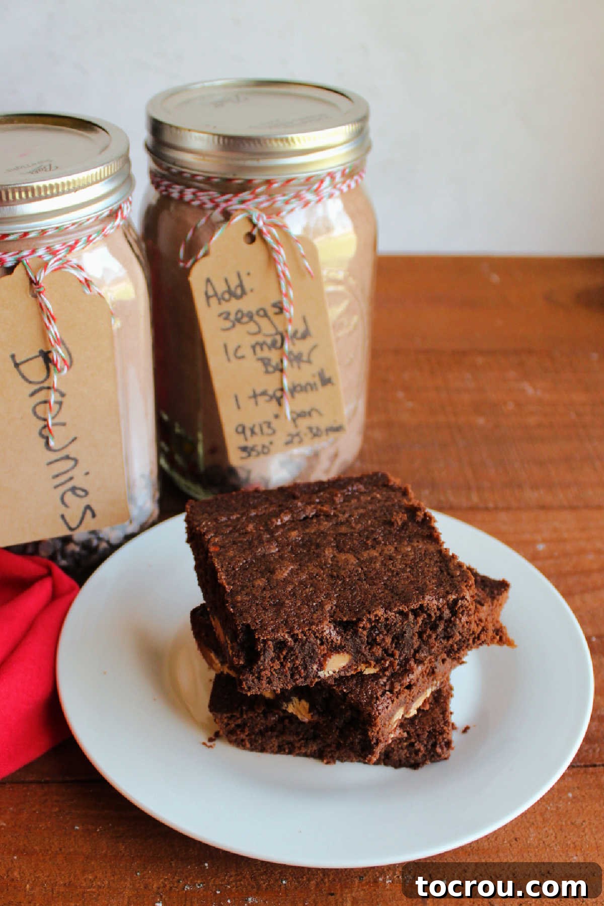 Plate of Brownies and Mix Jars A plate of chocolate brownies sits next to glass jars filled with homemade brownie mix, showcasing the delicious end product.