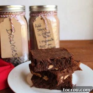 Homemade Brownie Mix Stack of homemade brownies in front of jars filled with brownie mix.