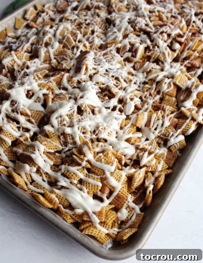 Tray of baked apple pie chex mix drizzled with white chocolate.