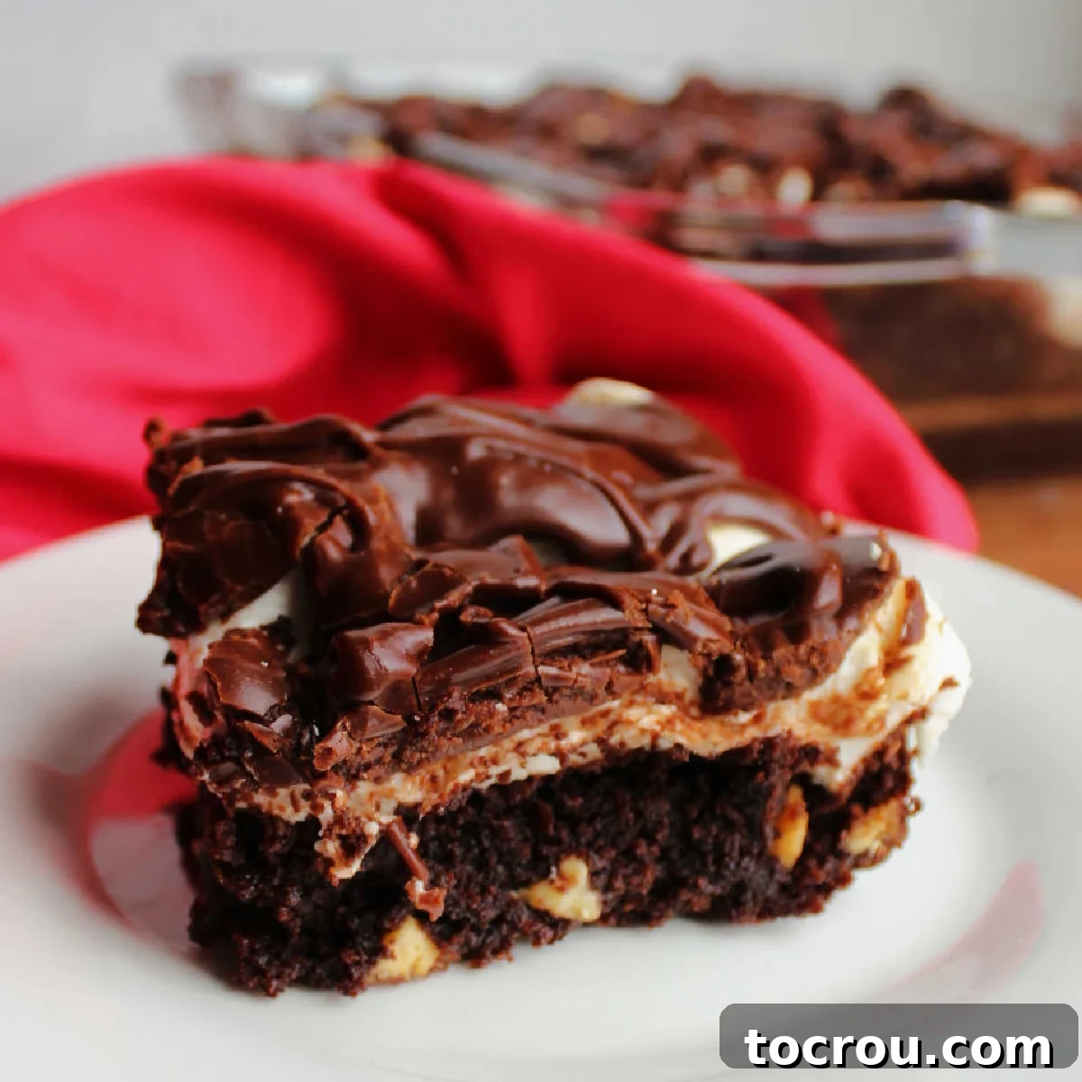 Close up of piece of mississippi mud brownies with layer of chocolate brownie, white marshmallow layer and chocolate icing on top.